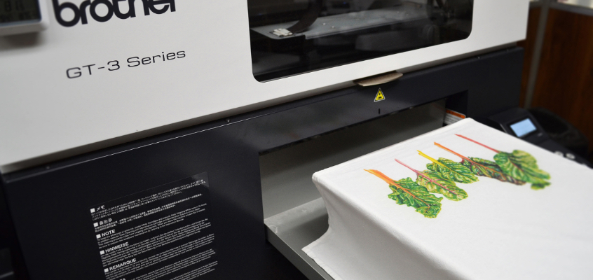 A screen printing machine printing trees onto a tea towel